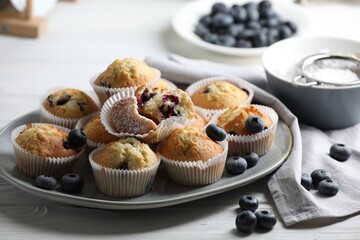 Delicious sweet muffins with blueberries on white wooden table