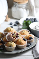 Delicious sweet muffins with blueberries on white wooden table
