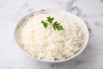 Bowl of delicious rice with parsley on light table, closeup