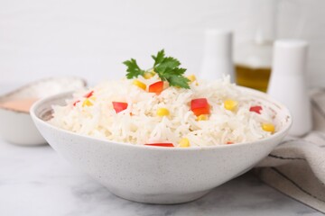 Bowl of delicious rice with vegetables and parsley on light table, closeup