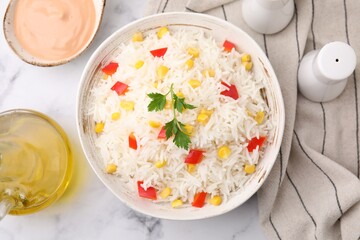 Bowl of delicious rice with vegetables and parsley on table, flat lay
