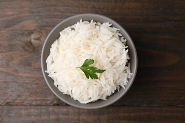 Bowl of delicious rice with parsley on table, top view