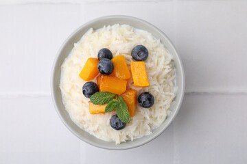 Bowl of delicious rice porridge with blueberries and pumpkin on white table, top view