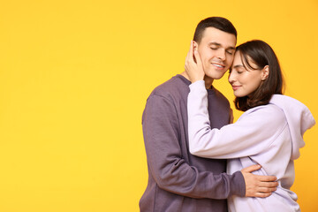 Cheerful young couple hugging on yellow background
