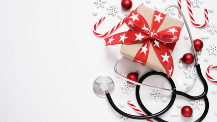 Christmas medical banner.Close-up of stethoscope,gift box,striped lollipops,red balls,stars and...