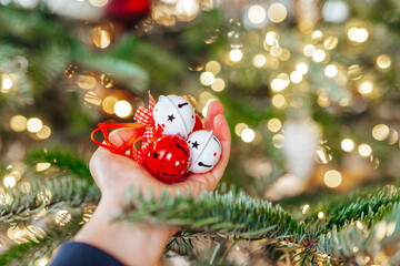 Christmas bells in hand.Christmas tree decoration with bells. White and red bells close-up. Christmas decorations on a Christmas tree background.
