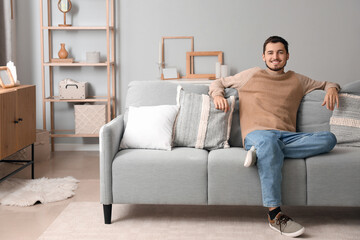 Fototapeta premium Young man sitting on sofa at home