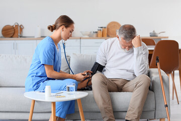 Nurse measuring blood pressure of senior man at home