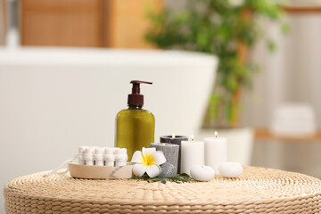 Obraz na płótnie Canvas Spa products, burning candles and plumeria flower on wicker table in bathroom
