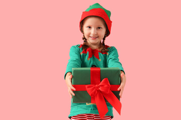 Cute little elf with Christmas gift on pink background