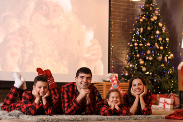 Happy family watching Christmas movie on projector screen at home