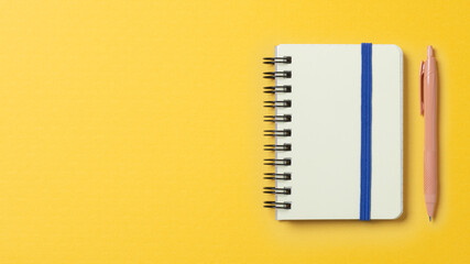 黄色い空間に置かれたノートとペン