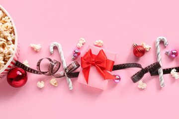 Bucket of popcorn with film reel and Christmas decor on pink background