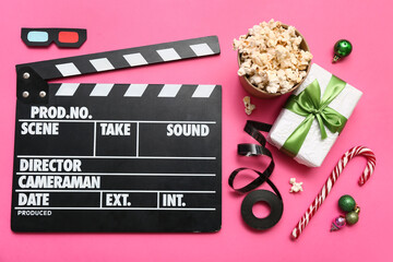 Movie clapper with popcorn, film reel and Christmas decor on pink background