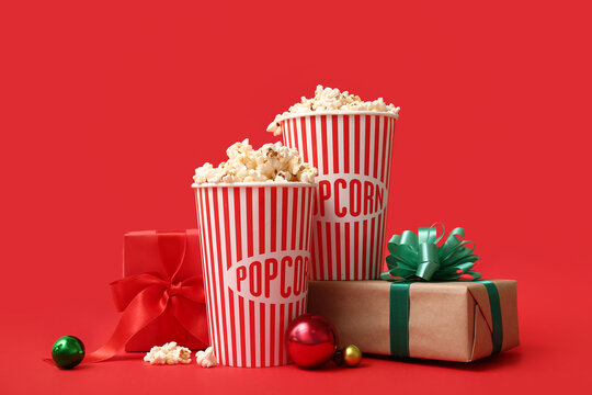 Buckets of popcorn with gifts and Christmas balls on red background