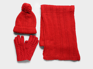 Red knitted gloves with warm scarf and hat on white background