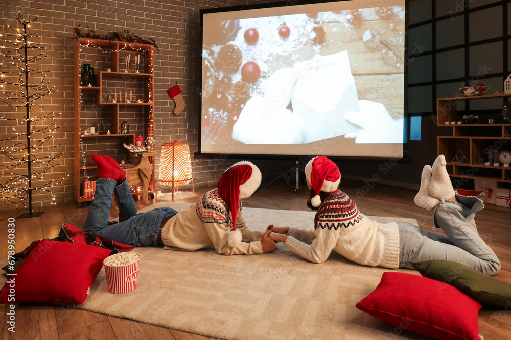 Poster Young couple watching Christmas movie on projector screen at home