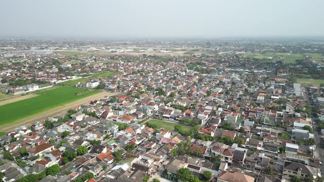 Aerial view of Solo City with buildings, crowded vehicles traffic in morning sunlight. Surakarta cityscape urban landscape. Population density is displacing agricultural land and forests.