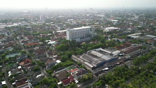 Aerial view of Solo Surakarta City with dense crowded buildings development in morning sunlight with smog or fog. Population density is displacing agricultural land and forests. Air Pollution