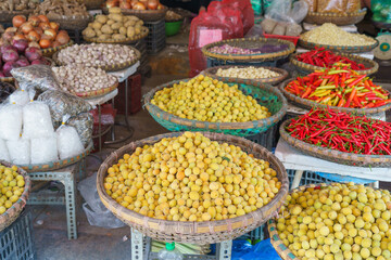 Baskets of different types of dried fruit, herbs, vegetables in an outdoor market on Hanoi street