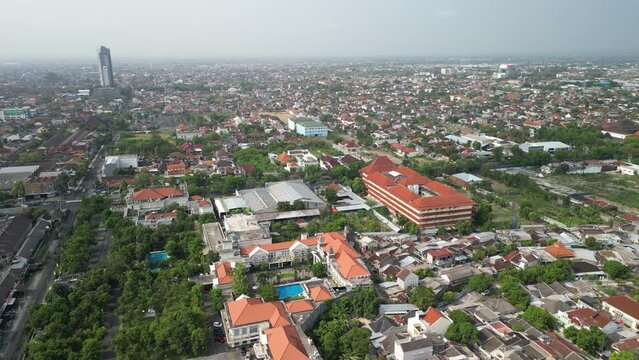 Aerial view of Solo Surakarta City with dense crowded buildings development in morning sunlight with smog or fog. Population density is displacing agricultural land and forests. Air Pollution