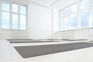 Spacious yoga studio with exercise mats and big windows, low angle view