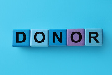 Word Donor made of cubes on light blue background, top view