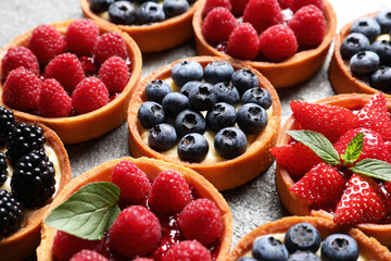 Tartlets with different fresh berries on table, closeup. Delicious dessert