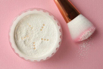 Rice loose face powder and makeup brush on pink background, flat lay