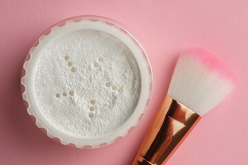 Fototapeta na wymiar Rice loose face powder and makeup brush on pink background, flat lay