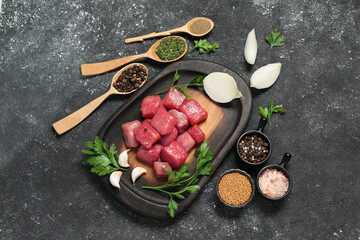 Obraz na płótnie Canvas Raw beef meat and different ingredients for cooking delicious goulash on black textured table, flat lay