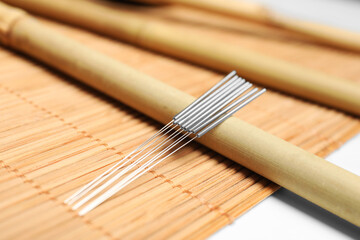 Many acupuncture needles on bamboo mat, closeup