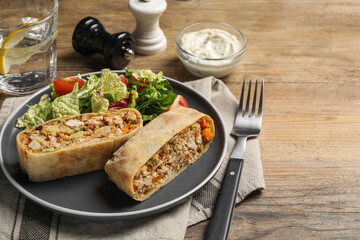Pieces of tasty strudel with chicken, vegetables and salad on wooden table. Space for text