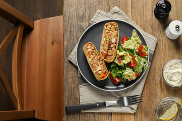 Pieces of tasty strudel with chicken, vegetables and salad served on wooden table, flat lay