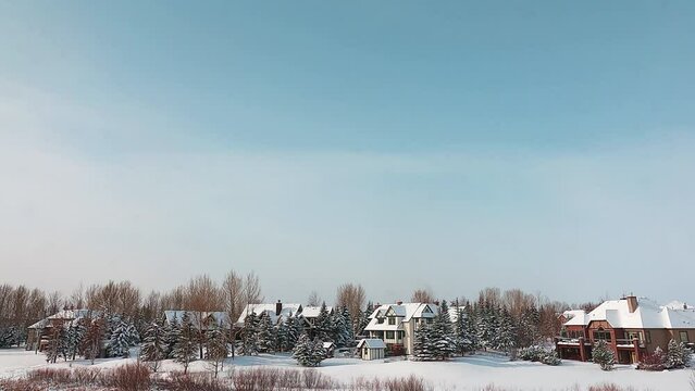 Winter scenery in the countryside in northern region Canada. Beautiful white snow covered the territory and houses. Soft pastel blue sky mix into white snow on the ground. Peaceful place landscape