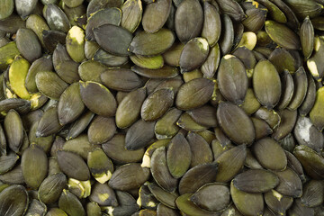 Many peeled pumpkin seeds as background, top view