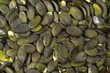 Many peeled pumpkin seeds as background, top view