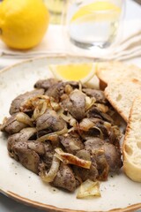 Tasty fried chicken liver with onion served on white table, closeup