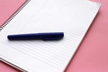 Notebook with pen on pink background. Work planning