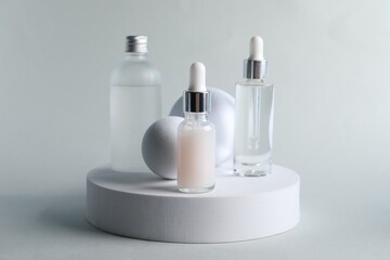 Fototapeta na wymiar Stylish presentation of bottles with cosmetic serums on light grey background
