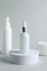 Bottles with cosmetic serums on light grey background