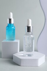 Presentation of bottles with cosmetic serums on light grey background