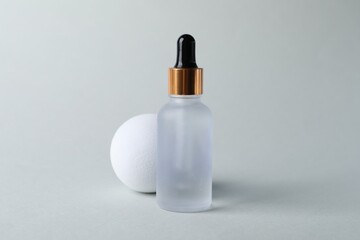 Bottle with cosmetic serum on light grey background