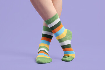 Woman in stylish colorful socks on violet background, closeup