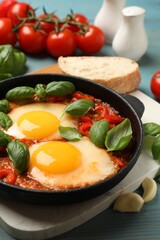 Delicious Shakshuka served on light blue wooden table, closeup