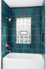 A bathroom shower detail with vibrant blue vertical glass subway tiles, a built-in niche, and a...