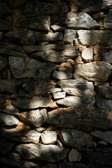 Stone wall with sunlight and shadow, close-up. Natural background