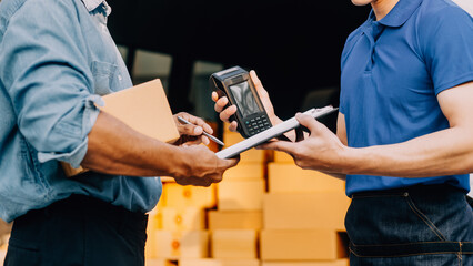 Asian delivery man in cargo van checking boxes.
