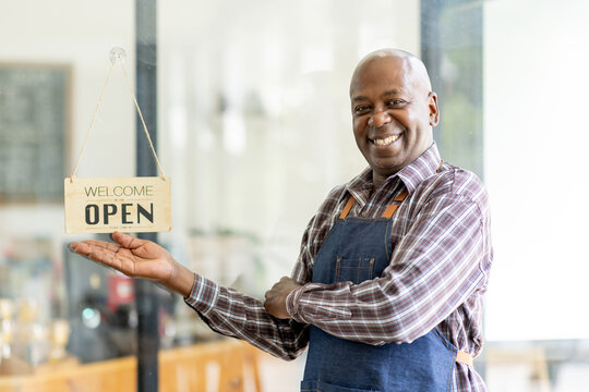 Financial freedom of small business Shot of a cheerful senior man smiling happily holding up an open sign posing at his own cafe in front of the door senior male standing his small business sme.