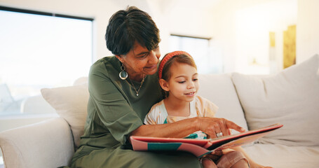 Grandmother, child and reading book on sofa for literature, education or bonding together at home. Grandparent with little girl or kid smile for story, learning or relax on living room couch at house